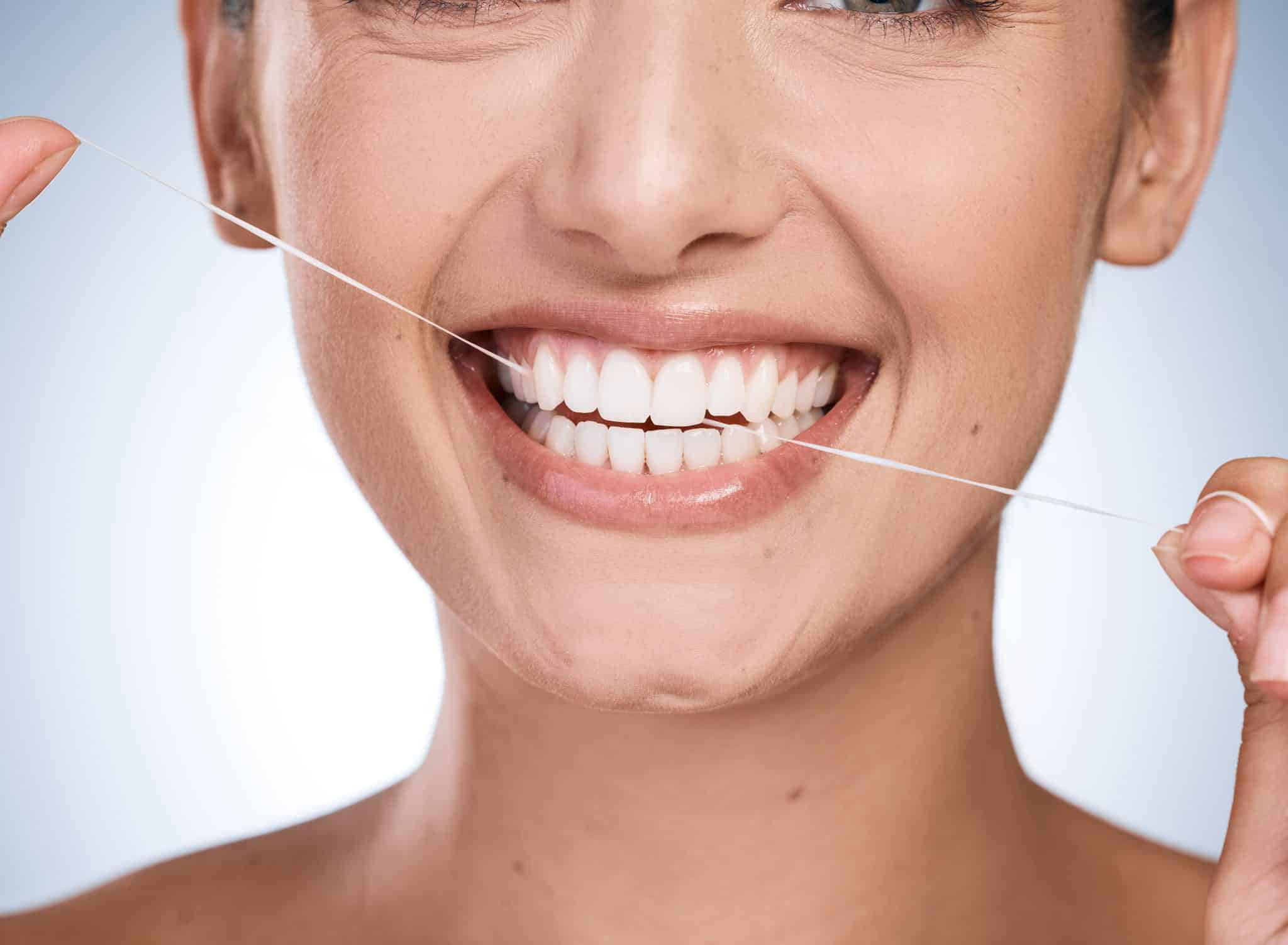 Woman smiling while flossing her teeth for for cosmetic dentistry