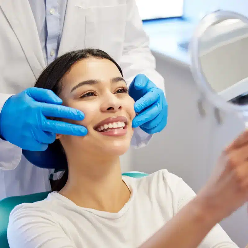 Dentist examining smiling woman's teeth in tooth whitening clinic for cosmetic dentistry