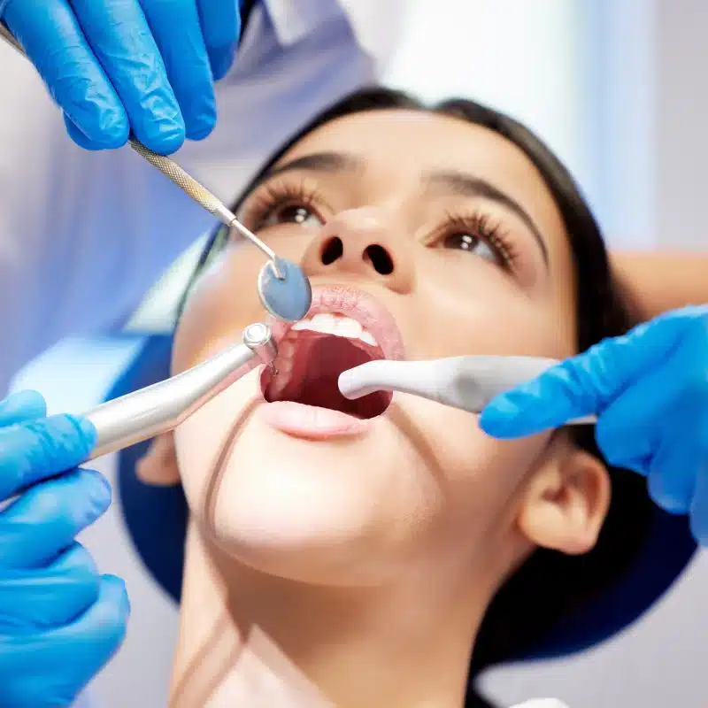 Dentist performing oral surgery on female patient