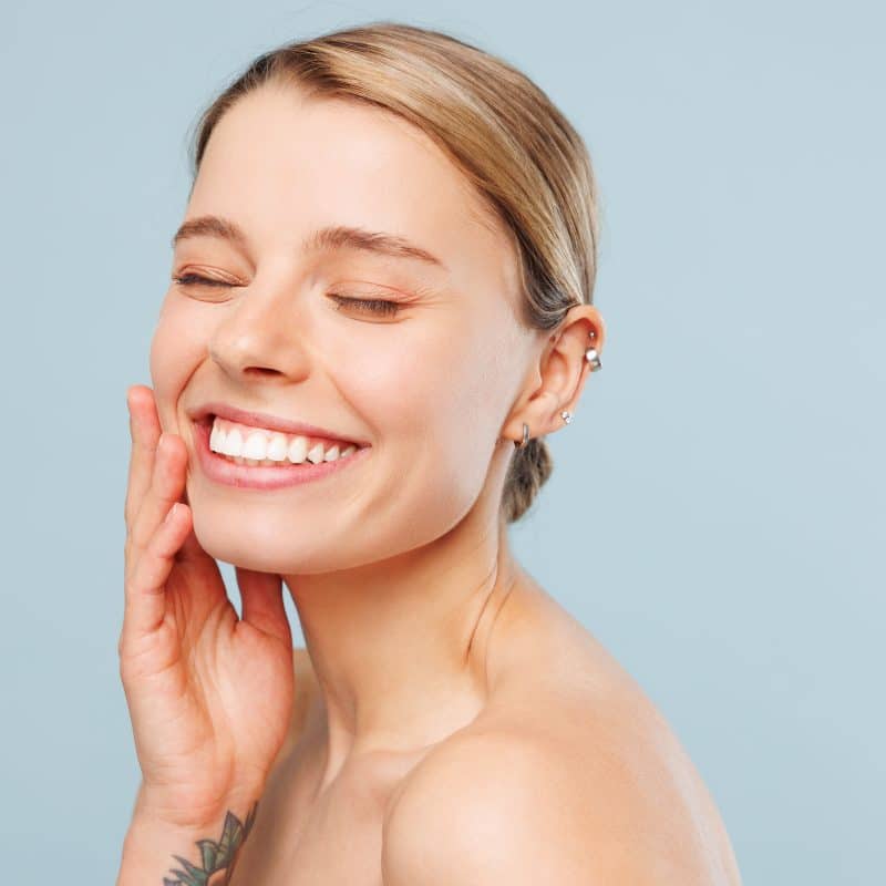 Happy woman smiling with a blue background for for cosmetic dentistry