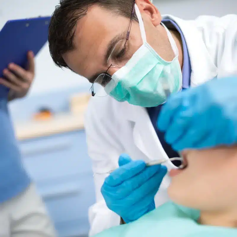 Dentist examining patient's teeth with assistant nearby orthodontic solutions