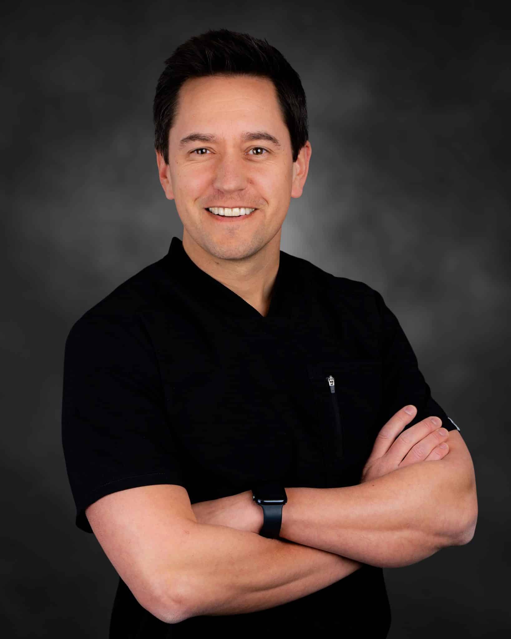 Smiling man in black shirt with arms crossed